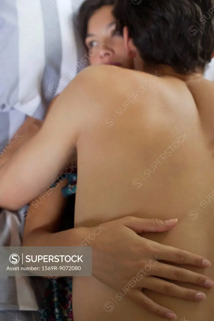 Naked young couple embracing in bed
