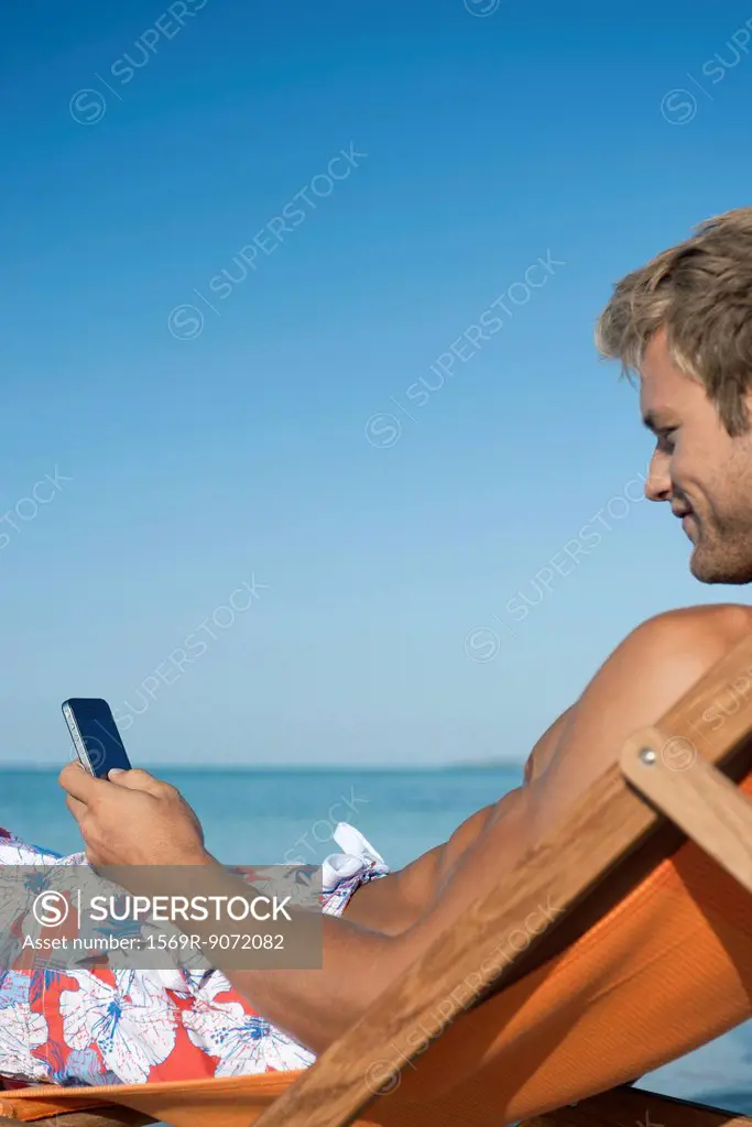 Young man text messaging at beach