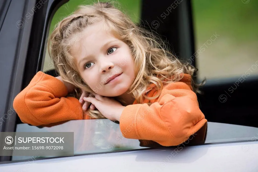 Little girl leaning out of car window, daydreaming, portrait