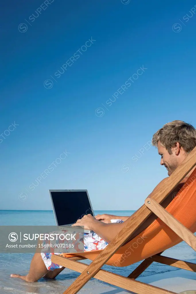 Young man using laptop on beach