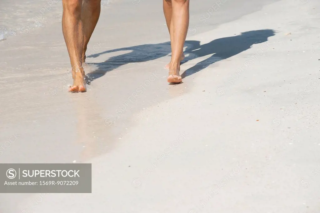 Couple walking on beach, low section