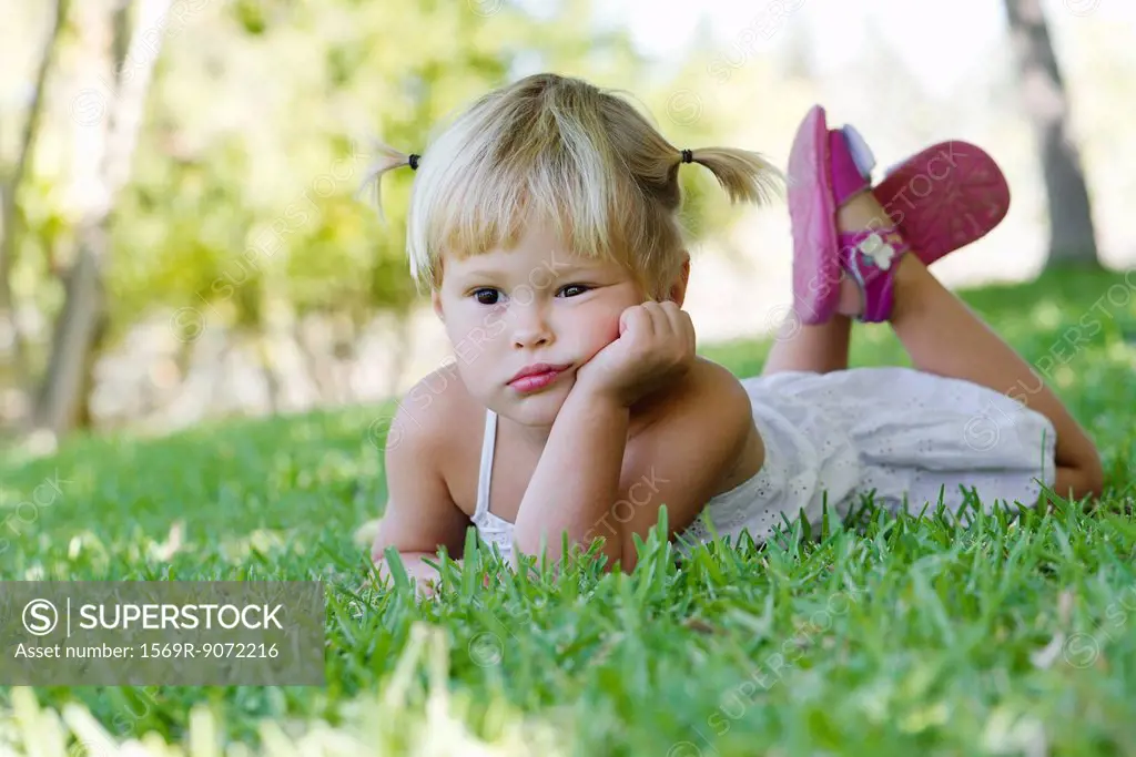 Little girl lying on grass, portrait