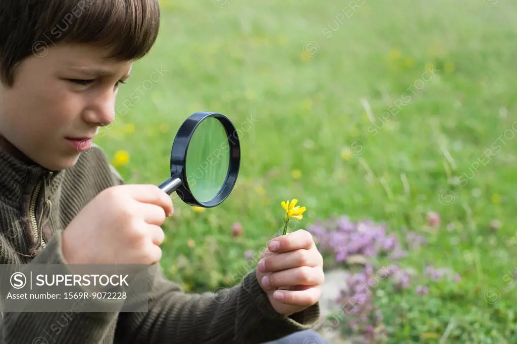 Boy looking at flower through magnifying glass