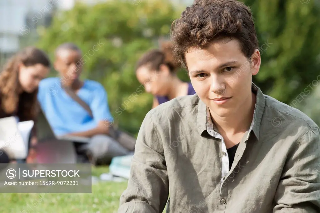 Young man outdoors, people in background, portrait