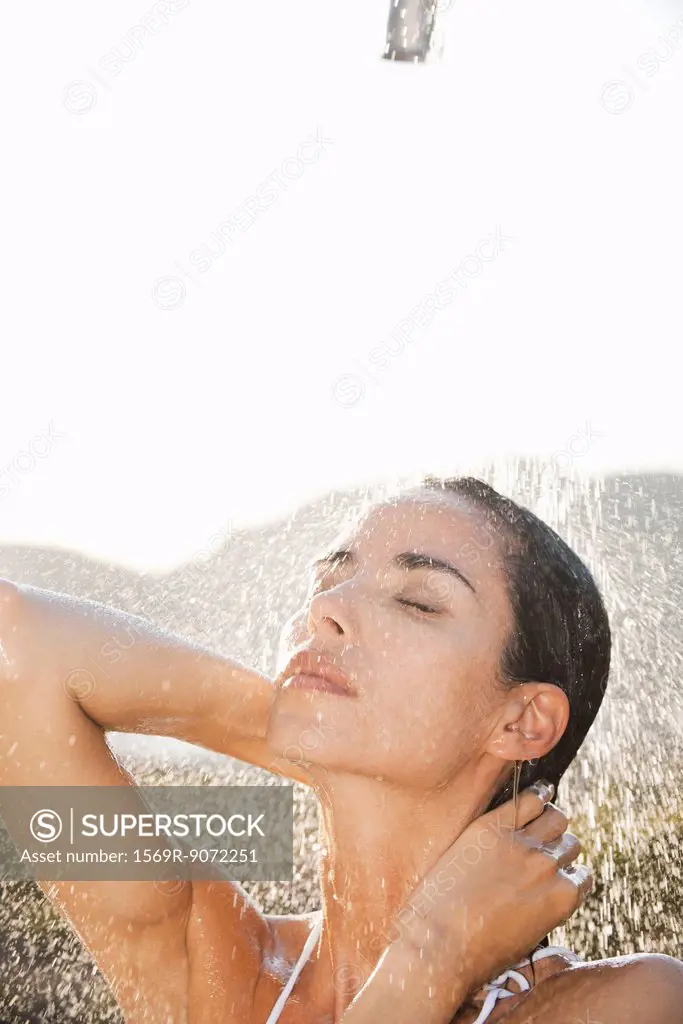 Mid_adult woman enjoying shower outdoors with eyes closed