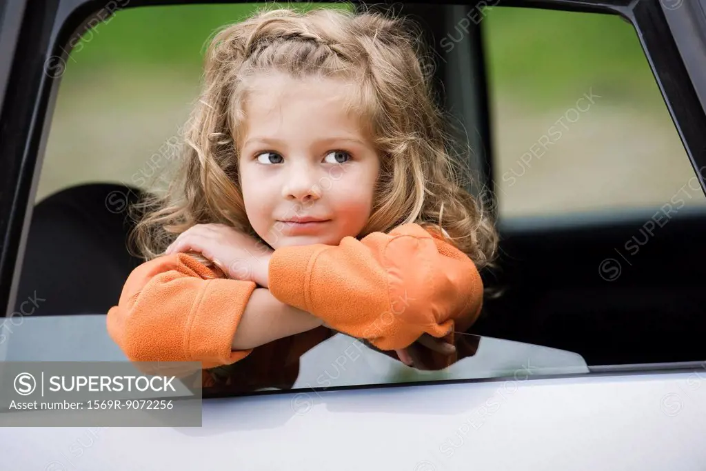 Little girl leaning out of car window, portrait