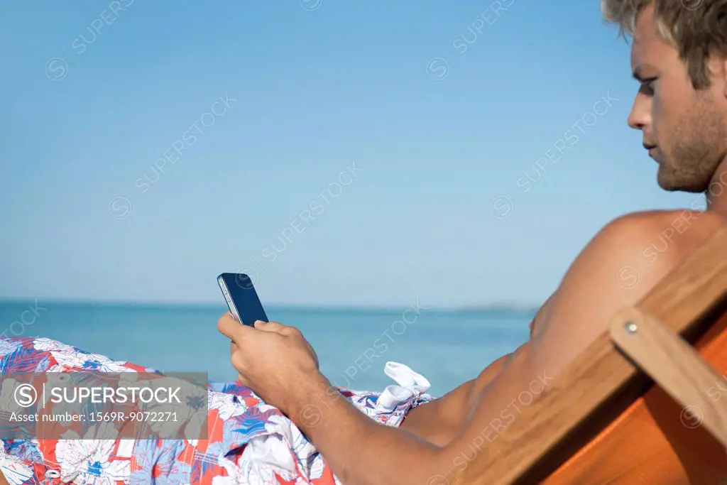 Young man text messaging on beach