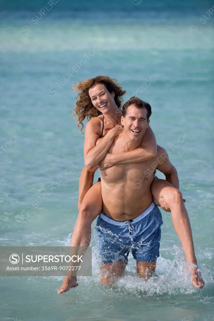 Man giving woman piggyback at beach