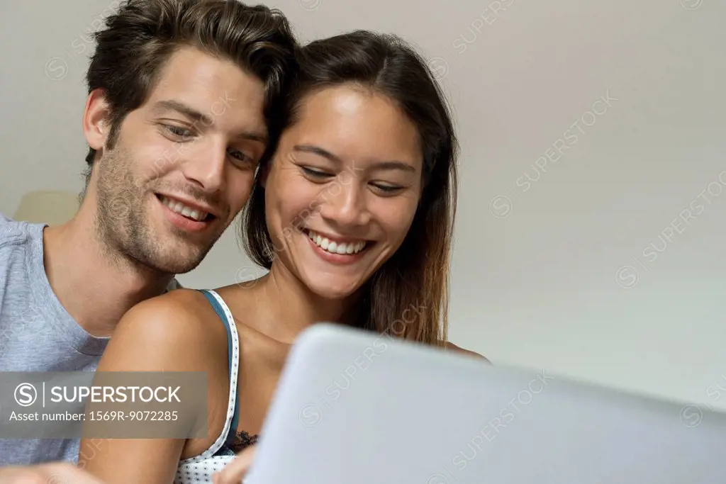 Young couple using laptop computer together, low angle view
