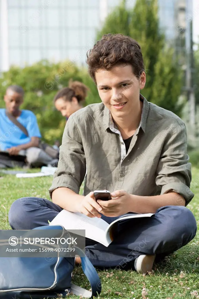 Young man with cell phone, friends in background, portrait