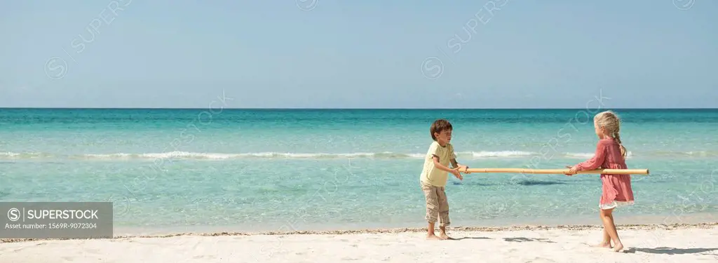 Children carrying bamboo together at the beach