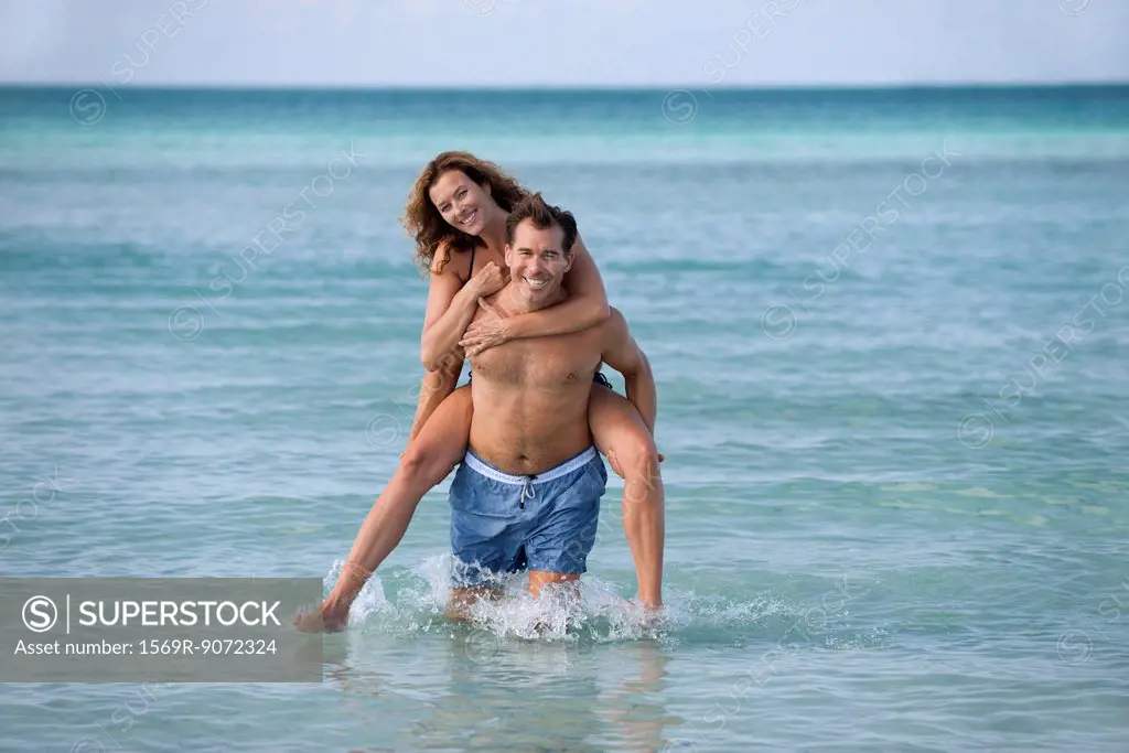 Man giving woman piggyback at beach, portrait