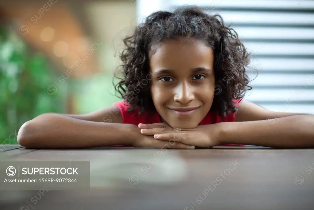 Girl with head resting on arms, smiling, portrait