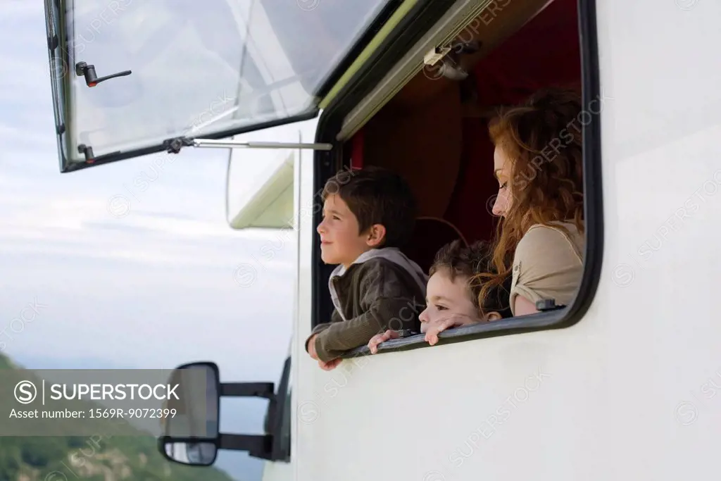 Mother and young boys looking out motor home window