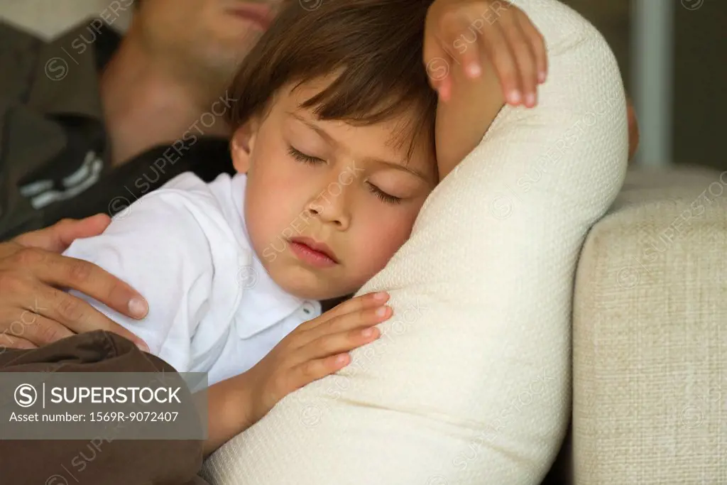 Boy napping on sofa with his father, cropped