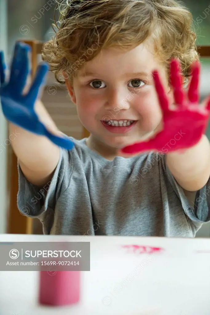 Little boy with hands covered in paint