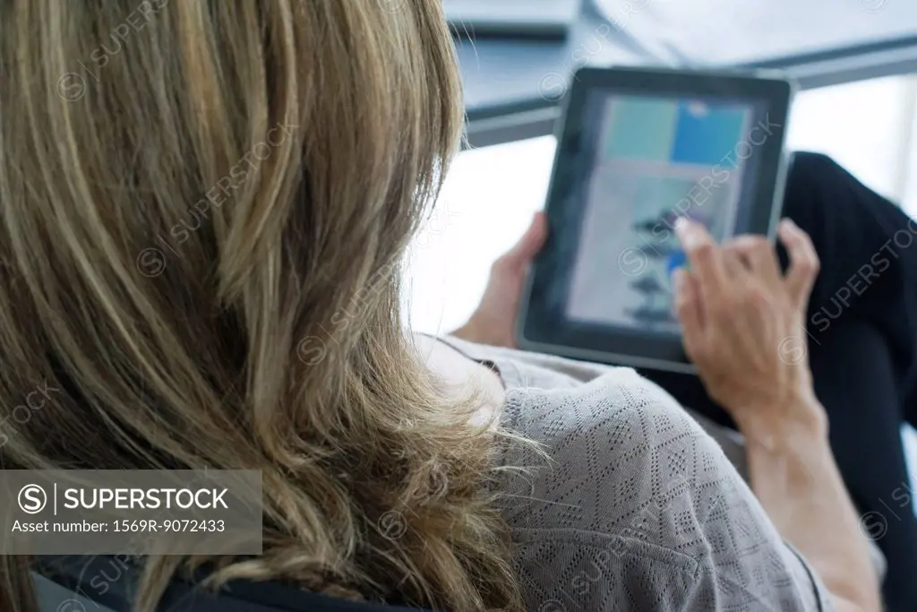 Woman using digital tablet, over the shoulder view