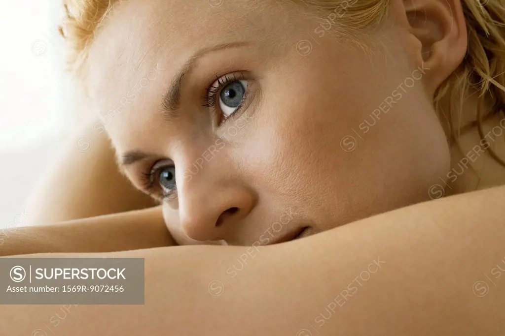 Woman resting head on arm, looking away in thought