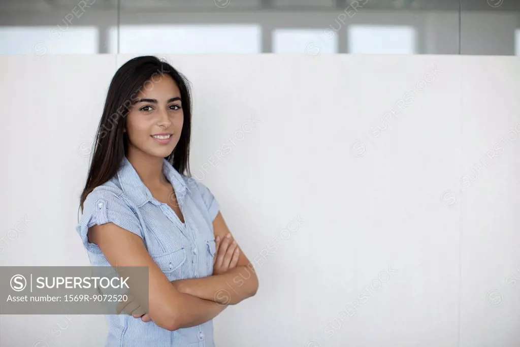 Smiling woman in office with arms folded, portrait