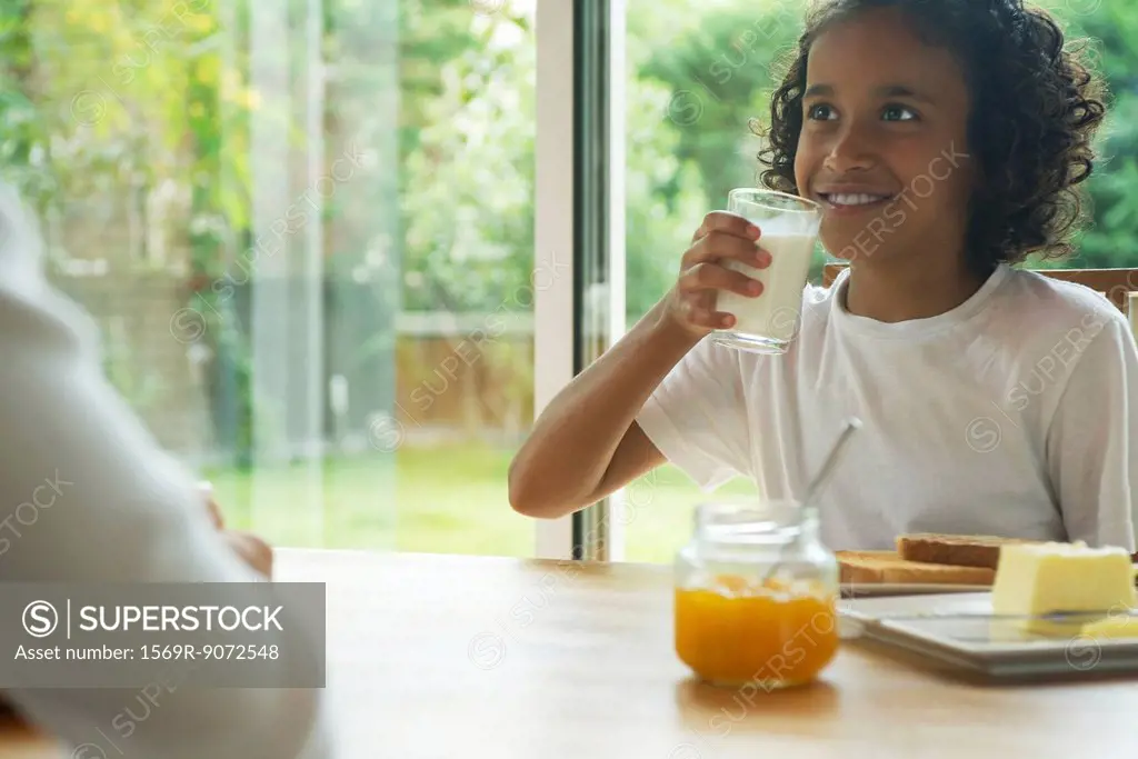 Girl drinking glass of milk at breakfast