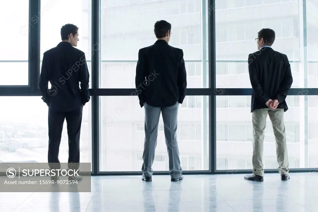 Executives standing side by side, looking out window