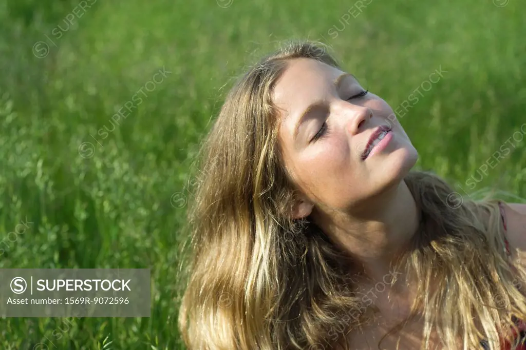 Young woman relaxing in field of grass