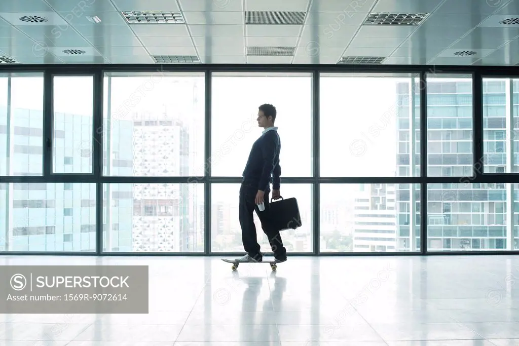 Businessman standing on skateboard with briefcase