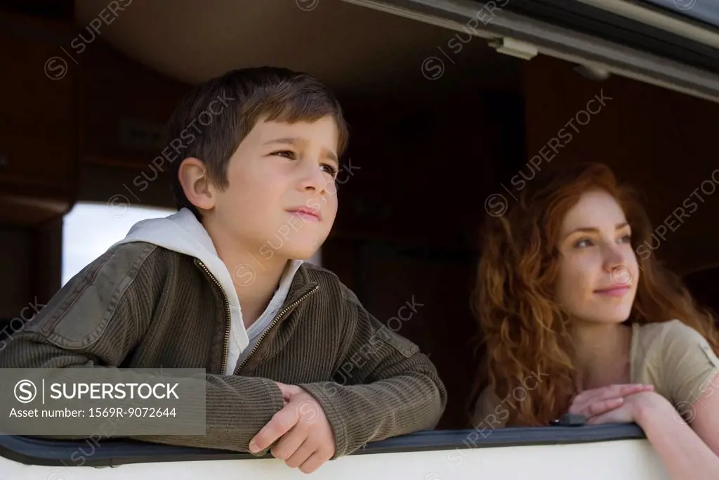 Young boy and mother looking out motor home window