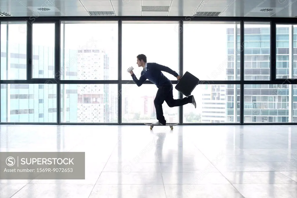 Businessman skateboarding with cup and briefcase in hands