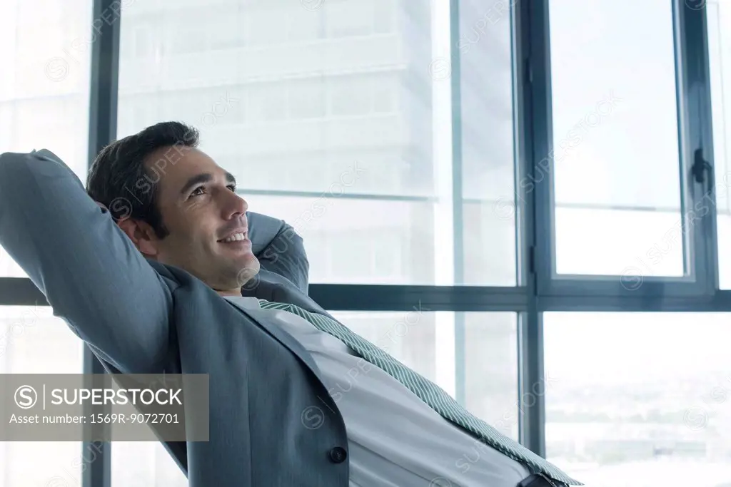 Business executive relaxing with hands behind head