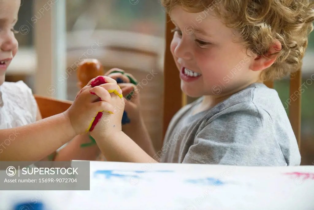 Young children holding hands while finger painting