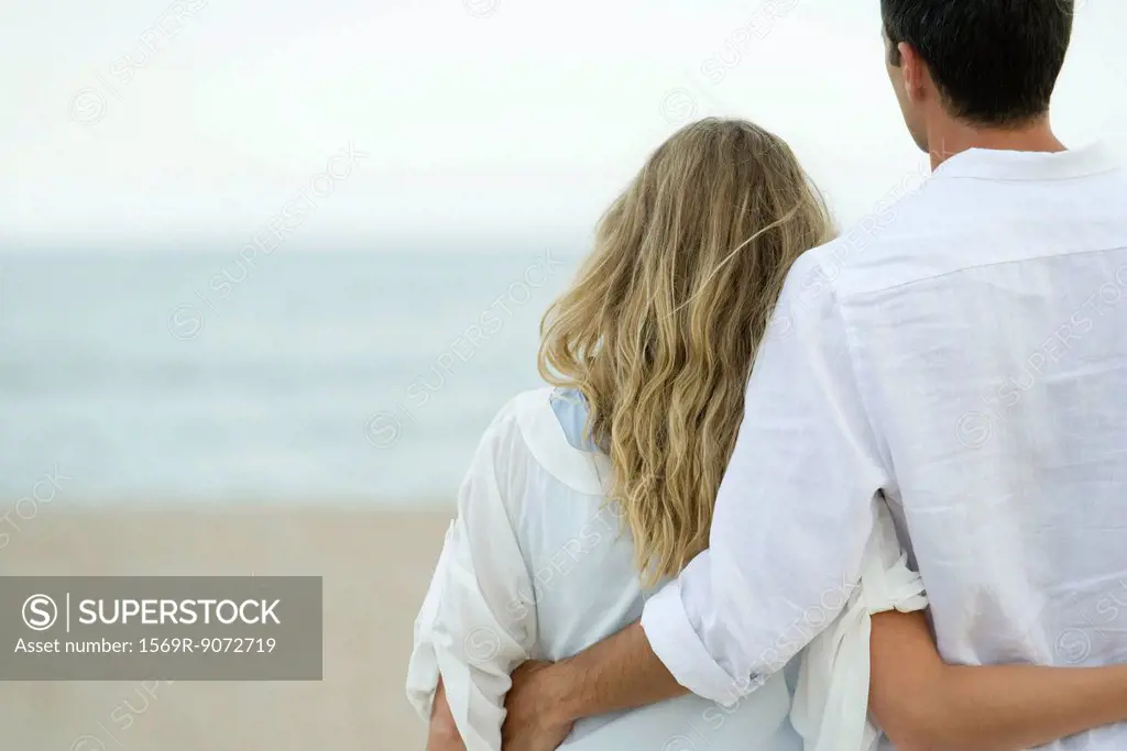 Couple standing together at beach, rear view