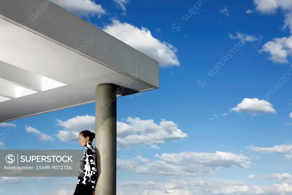 Fashionably dressed young woman leaning against portico column