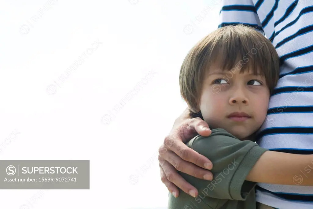 Boy embracing his father, looking away in thought