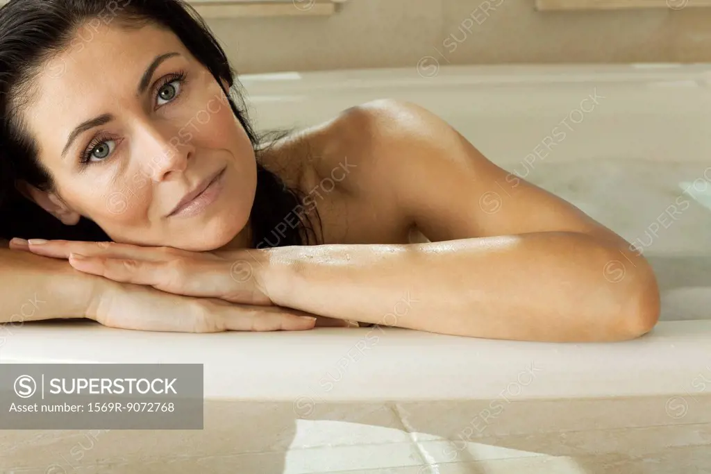 Woman resting head on arms relaxing in bath