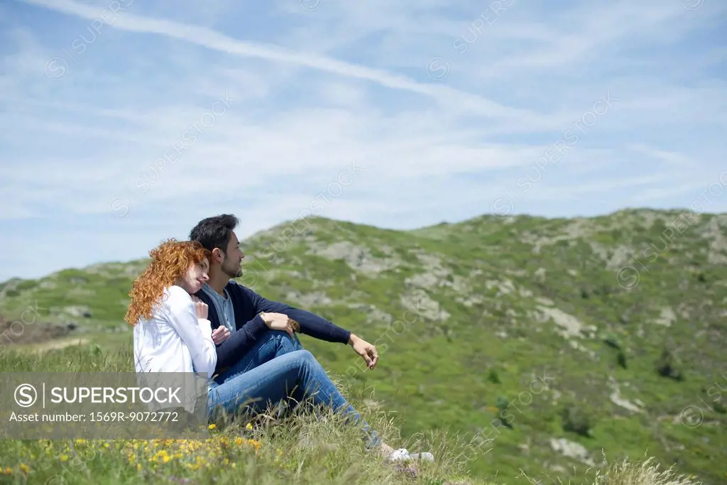 Couple sitting on meadow, side view
