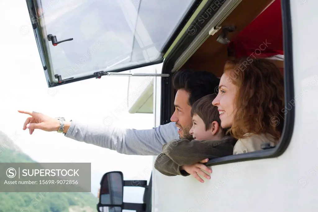 Parents with young son in motor home, father pointing into distance