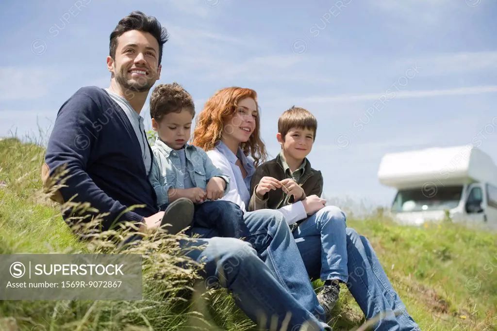 Parents and young boys sitting on meadow