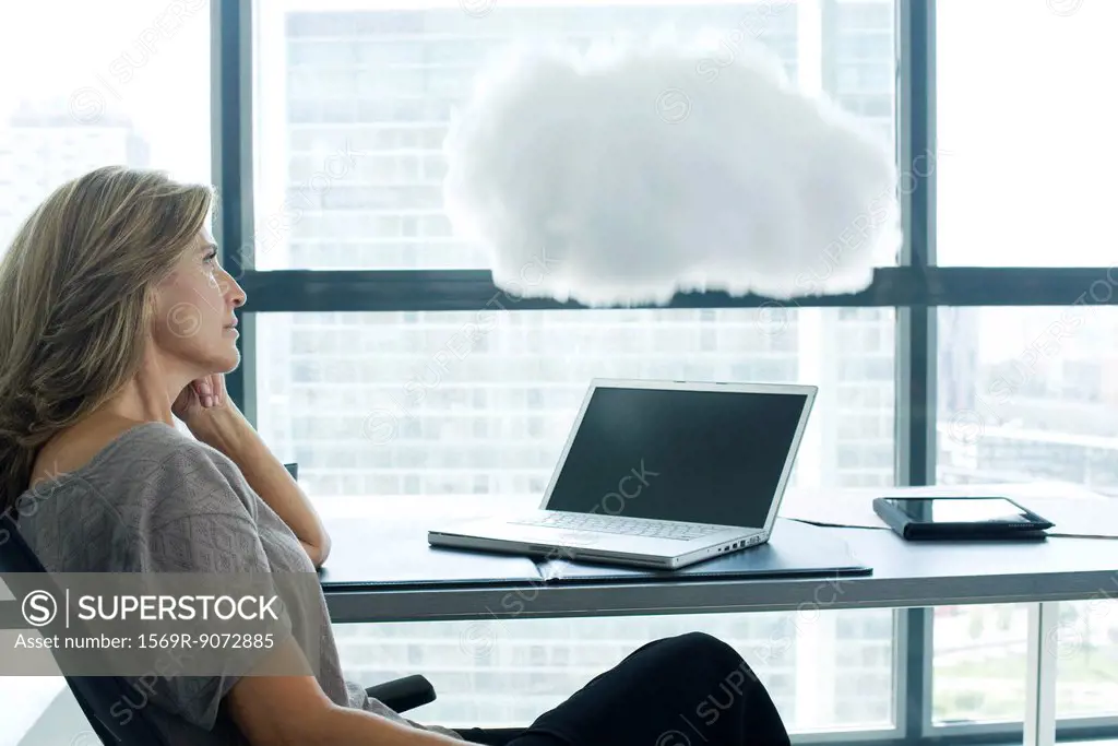 Woman sitting at desk with laptop computer. cloud above laptop computer
