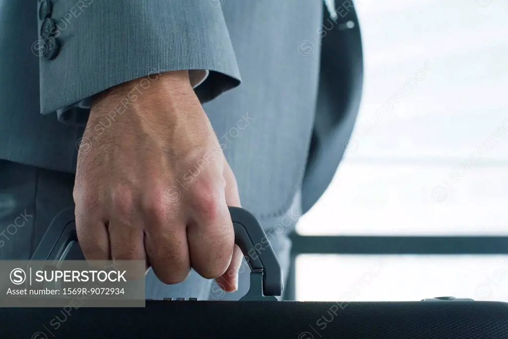 Executive´s hand carrying briefcase, mid section, close_up