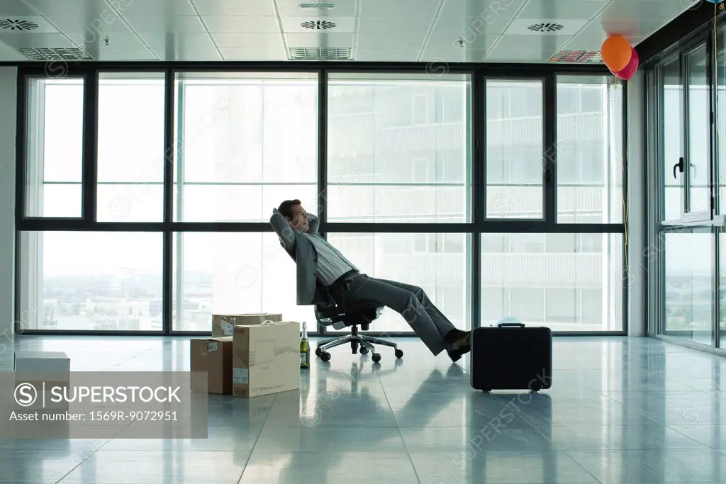 Businessman sitting in empty office with boxes on floor
