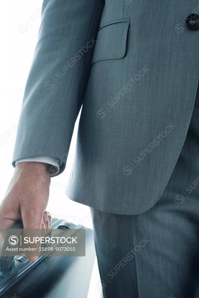 Executive carrying briefcase, mid section