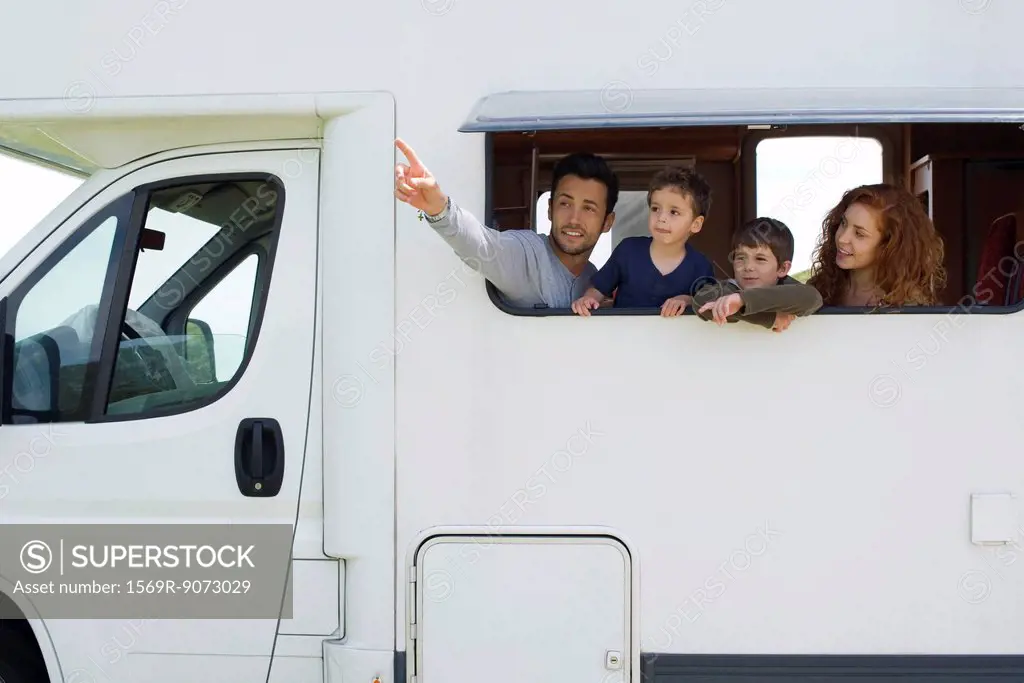 Parents and young boys in motor home, father pointing into distance