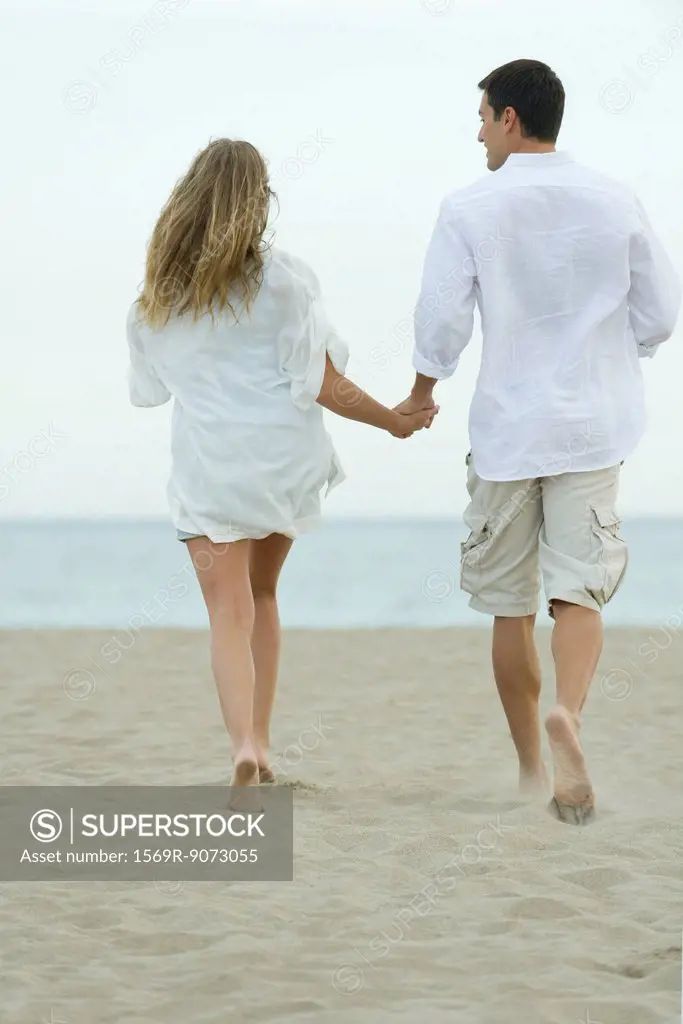 Couple walking together on beach, rear view