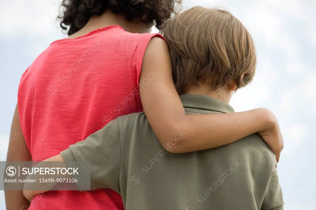 Young siblings embracing, rear view
