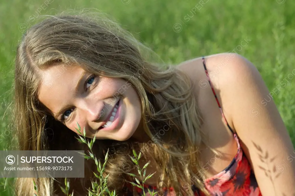 Young woman relaxing in tall grass, portrait
