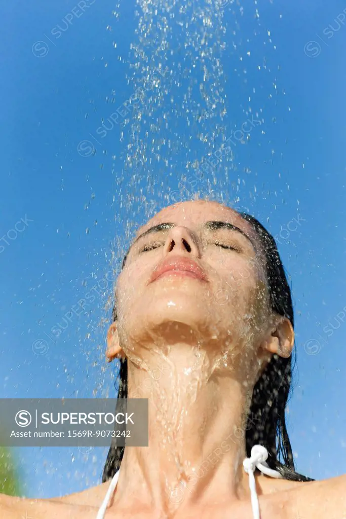 Mid_adult woman under shower outdoors with eyes closed
