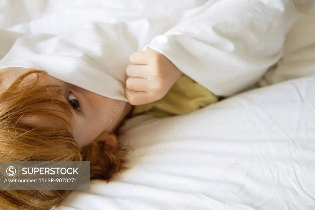 Boy hiding under bedsheet