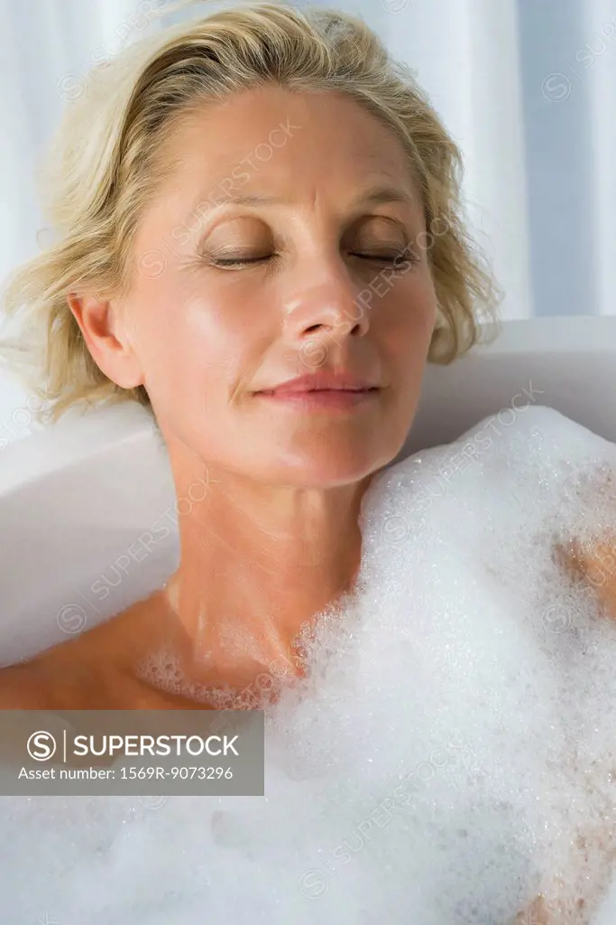 Mature woman relaxing in bubble bath with eyes closed, portrait