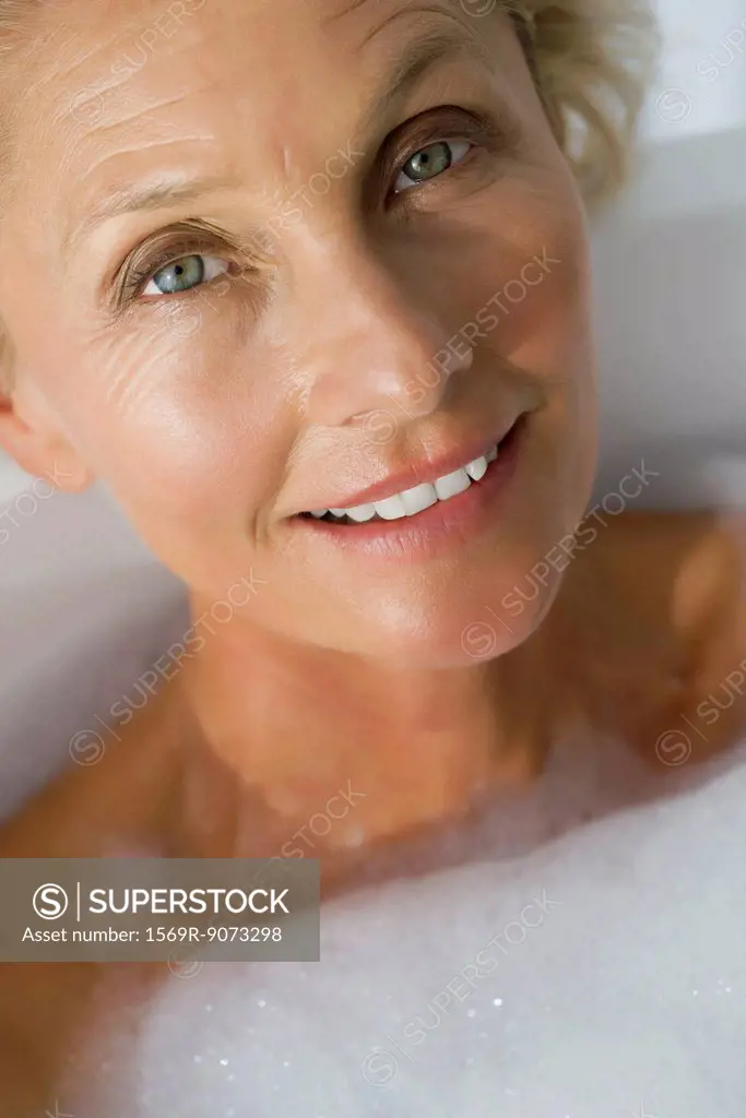 Mature woman relaxing in bubble bath, cropped